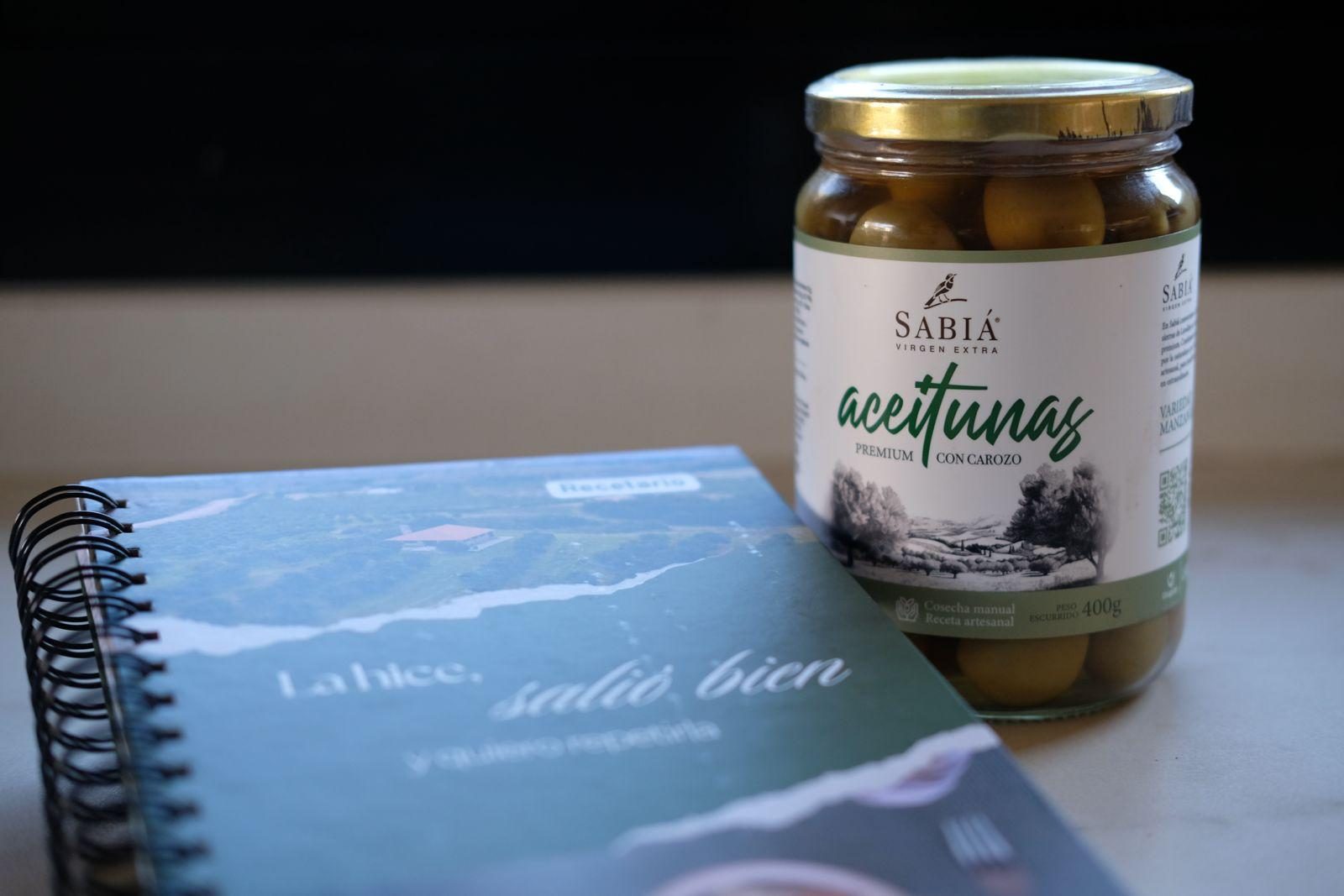 El recetario Sabiá y un frasco de aceitunas Manzanilla sobre la mesa