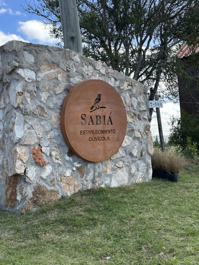 El cartel de acceso al establecimiento Sabiá, en acero corten sobre un muro de piedra